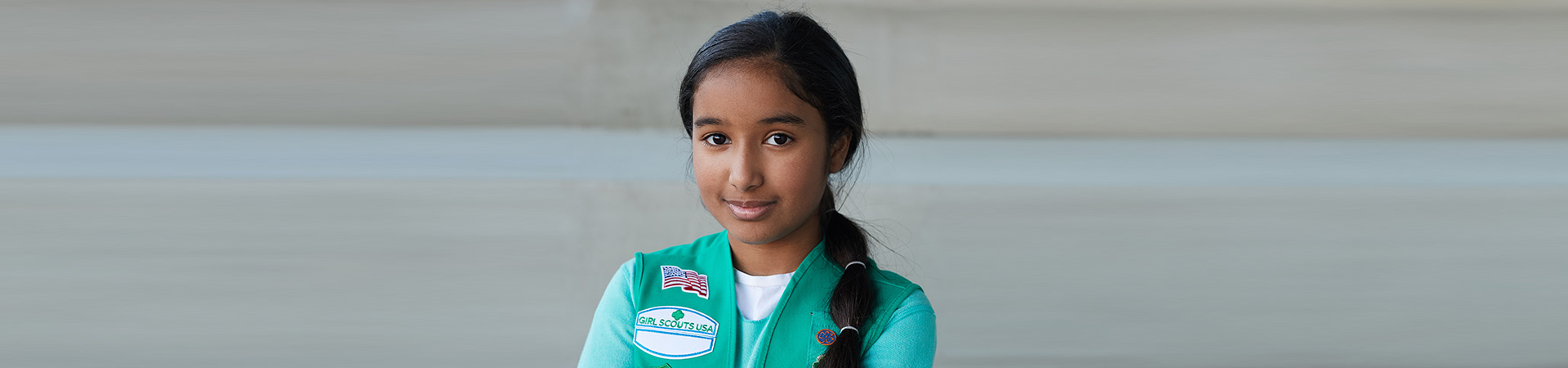  junior girl scout wearing uniform vest with bronze award pin 